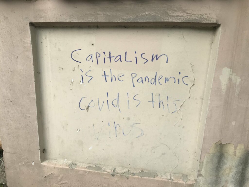 Angliškas grafitis: Kapitalizmas yra pandemija. COVID yra šitas virusas.