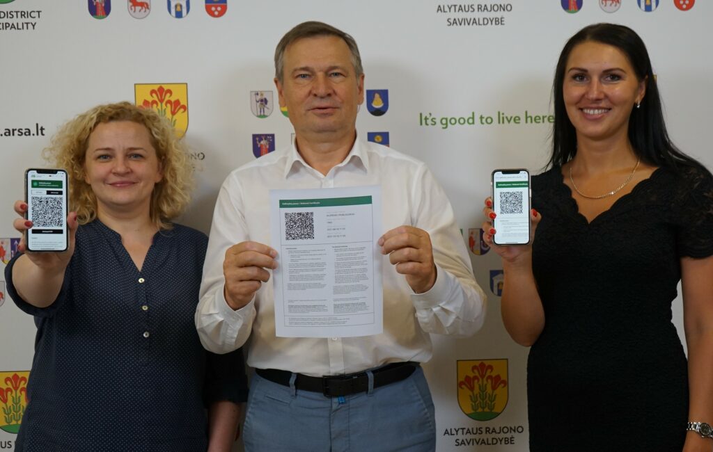 Trys žmonės rodo galimybių paso versijas telefonuose ir ant popieriaus