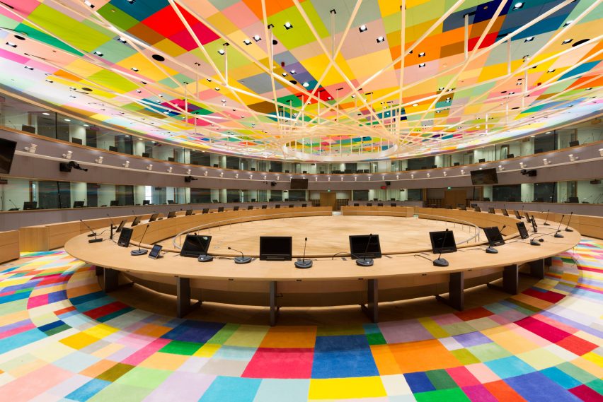Europos Komisijos pagrindinė posėdžių salė, medinis apskritas stalas ir spalvingos grindys