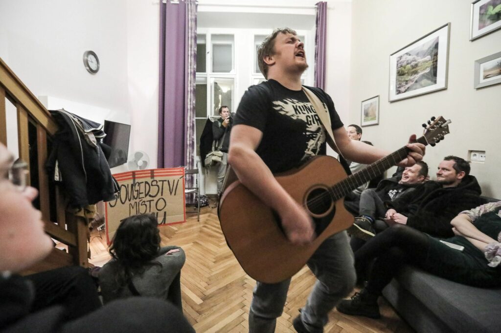 A guy with a guitar singing during the stop AirBnB action