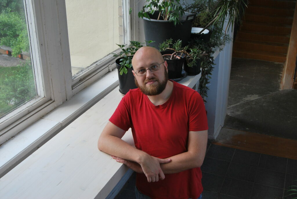 Tomas Marcinkevičius su raudonais marškinėliais, pasirėmęs ant palangės