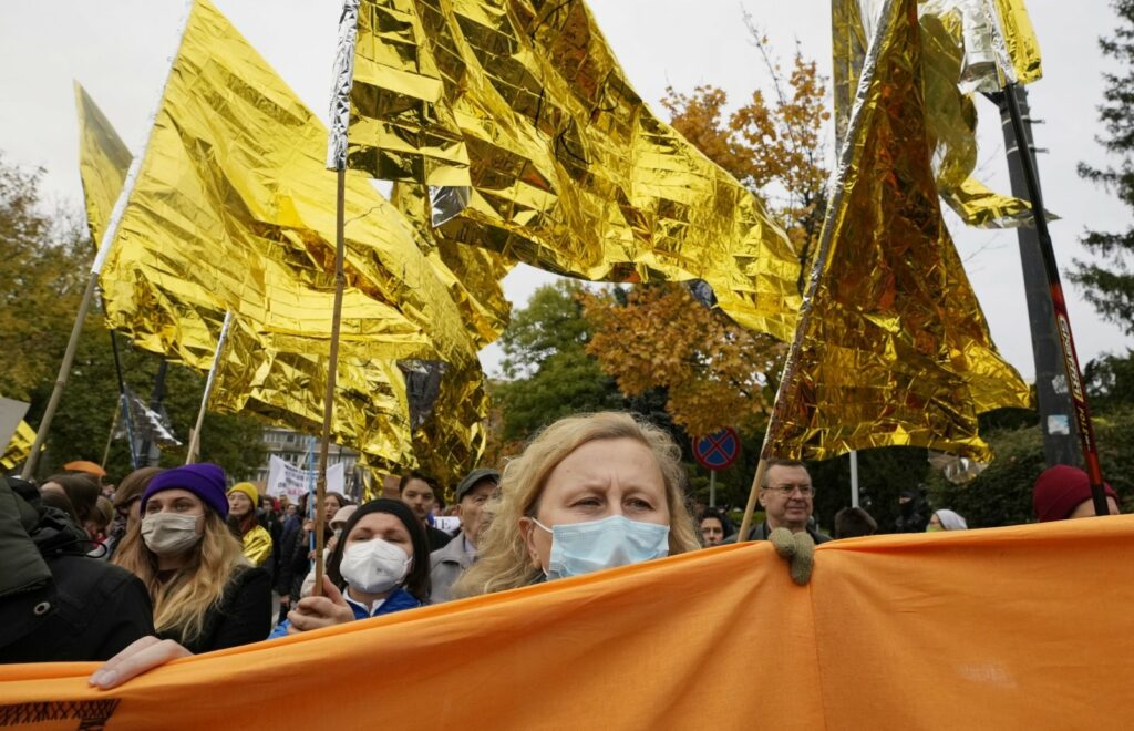 žmonės proteste su auksinėmis vėliavomis