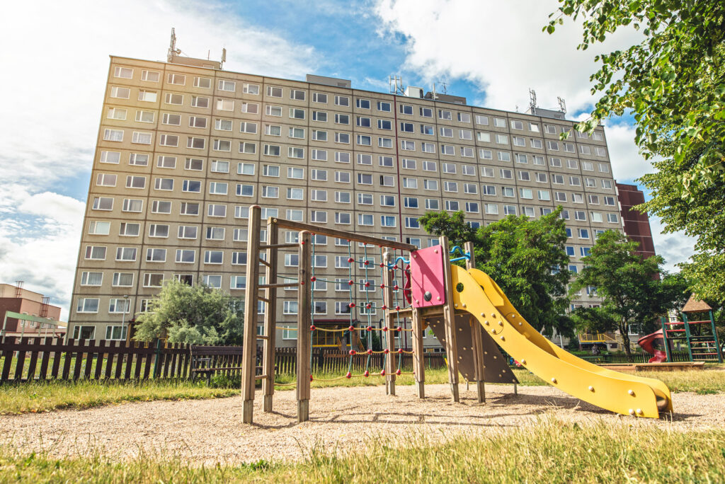 a children's playground with a slide in front of a block of flats