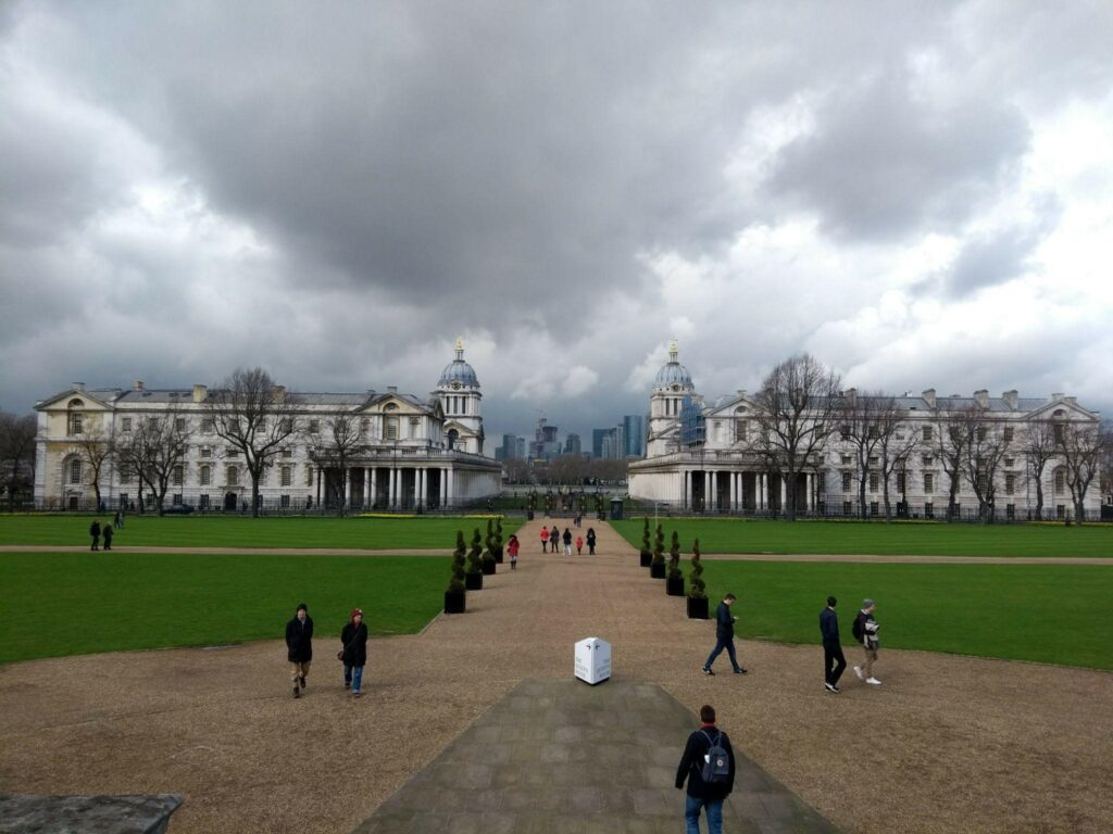 cloudy skies, a palace, a square where people walk