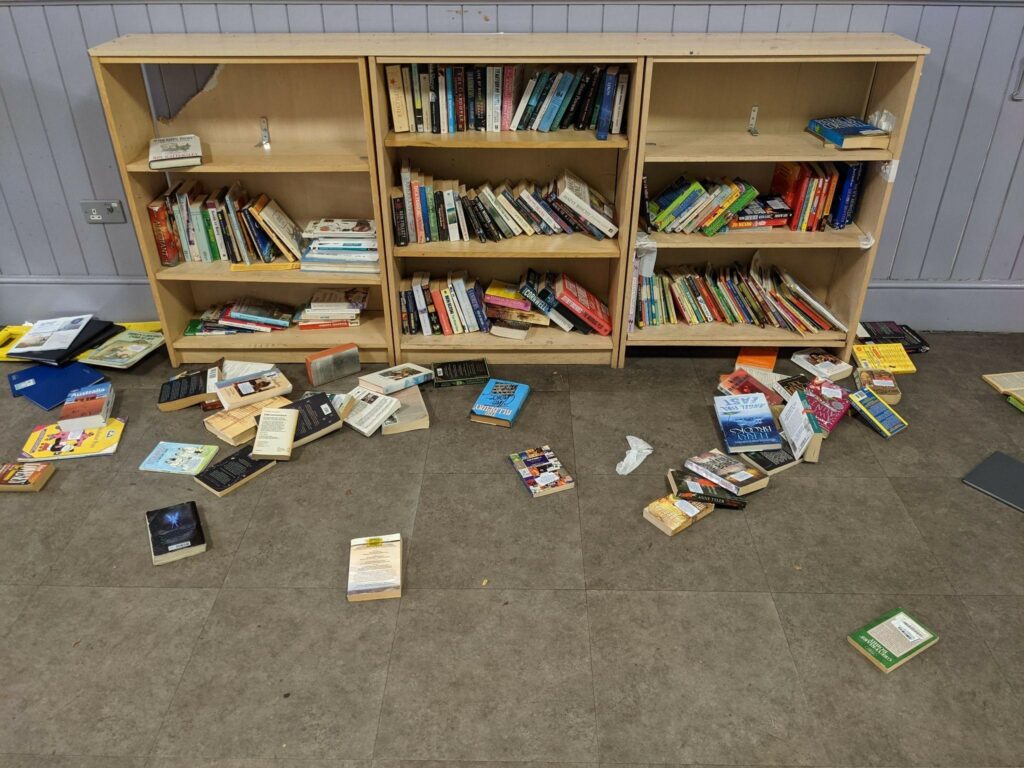 Lentyna su knygomis, dalis jų išmėtyta ant grindų