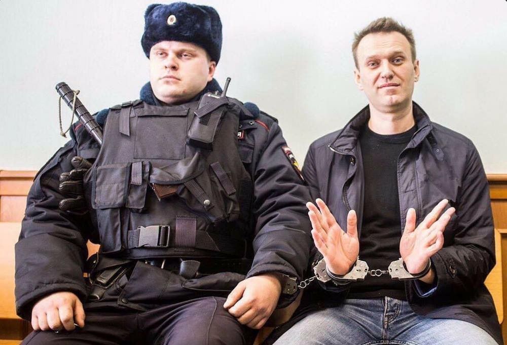 Rusijos milicininkas ir prie jo antrankiais prirakintas Aleksejus Navalnas