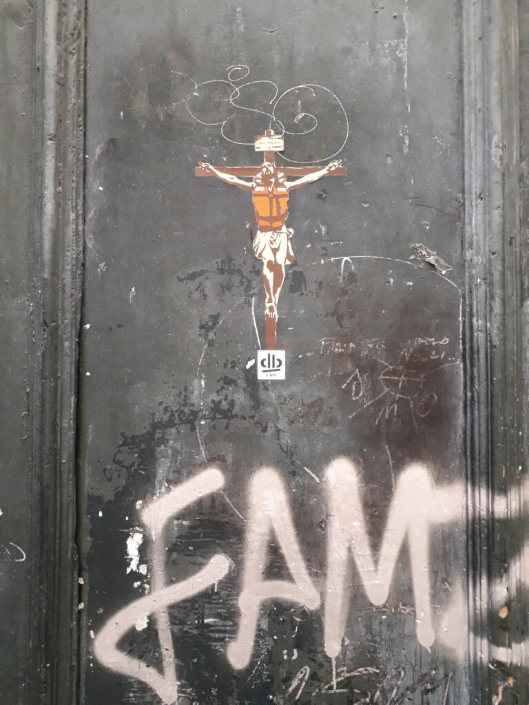 Tamsiaodis migrantas pavaizduotas kaip nukryžiuotasis ant bažnyčios durų